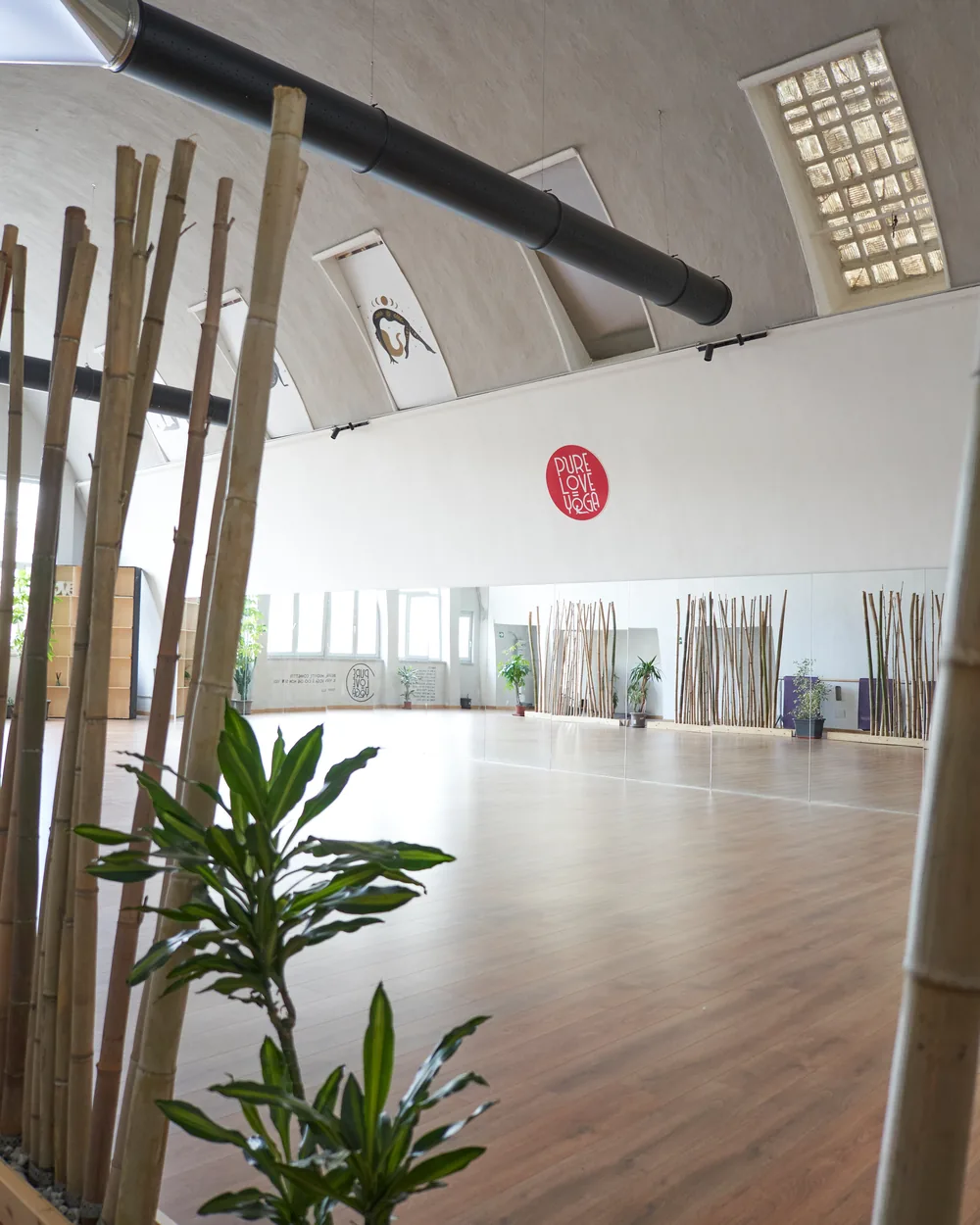 La sala di Via Bogetto vista attraverso le canne di bambù, con gli specchi e il logo rosso in fondo