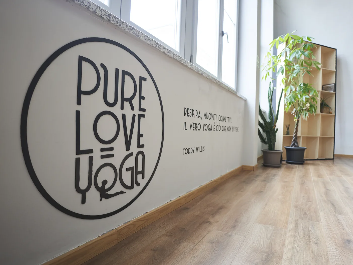 Il corridoio d'ingresso di Via Bogetto, con il logo Pure Love Yoga dipinto sulla parete e la frase «Respira, muoviti, connettiti»