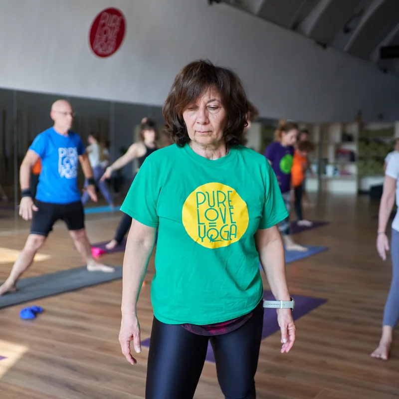 Allieva con la maglietta verde Pure Love Yoga in piedi durante la lezione