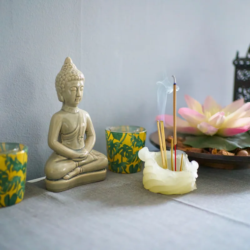 Piccolo altare con Buddha, candele e incenso acceso
